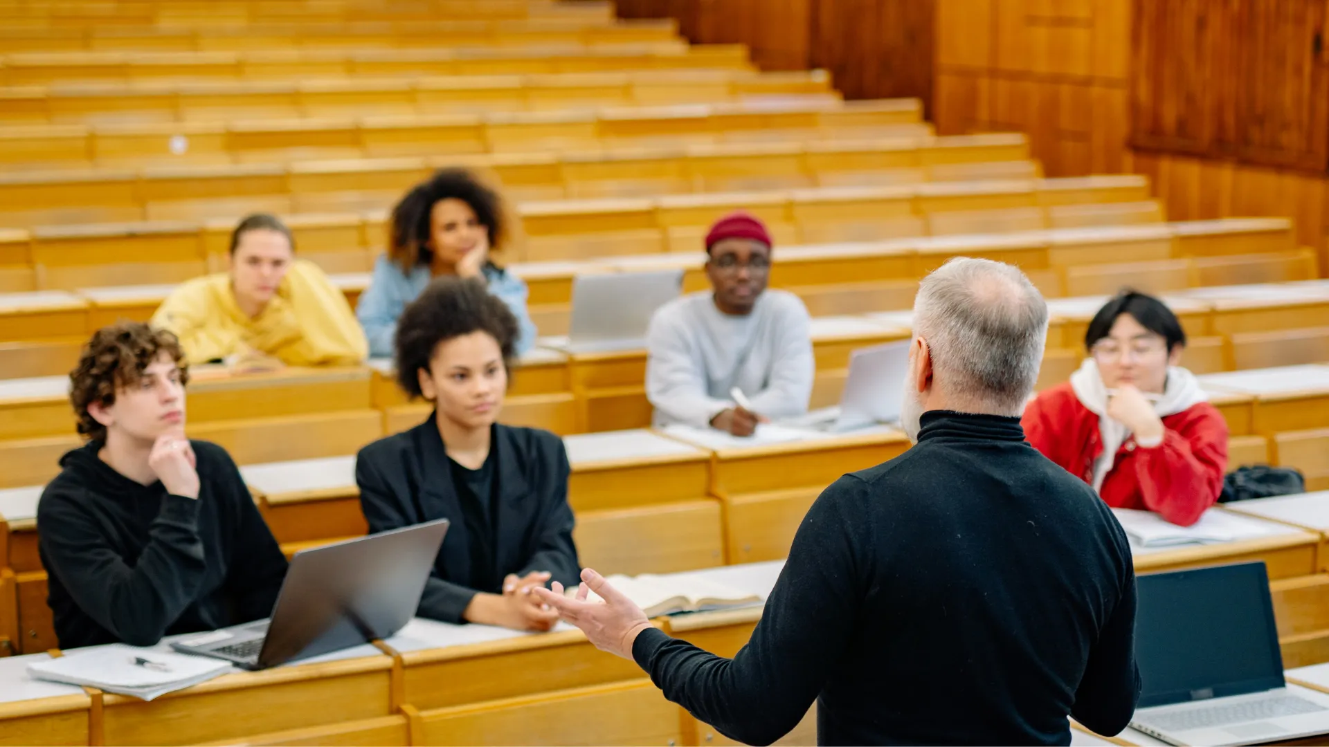 Expanding reach through education and systems change Training lecturer speaking in a lecture hall in front of a group of people.