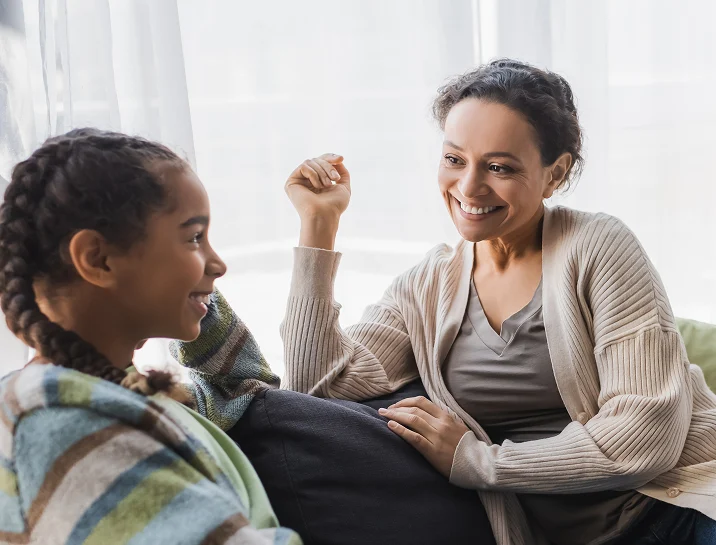 Mother and daughter sitting on couch happily enjoying a moment togther.